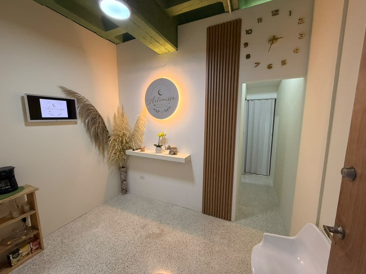 Recepción de Artemissa Wellness Studio con logo iluminado y detalles botánicos